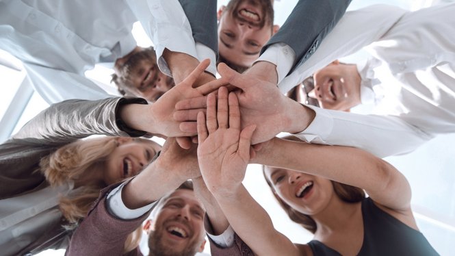 Home Gruppe lächelnder Menschen legt Hände zusammen im Teamwork