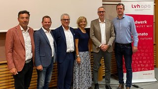 News Sei persone in piedi insieme davanti a uno schermo e un banner Lvh Apa