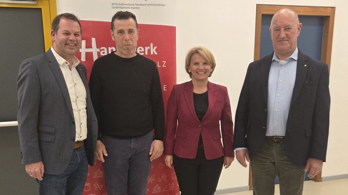 Mittelschule Dorf Tirol: Berufe praxisnah erleben Vier Personen vor LVH APA Banner in einem Gebäude