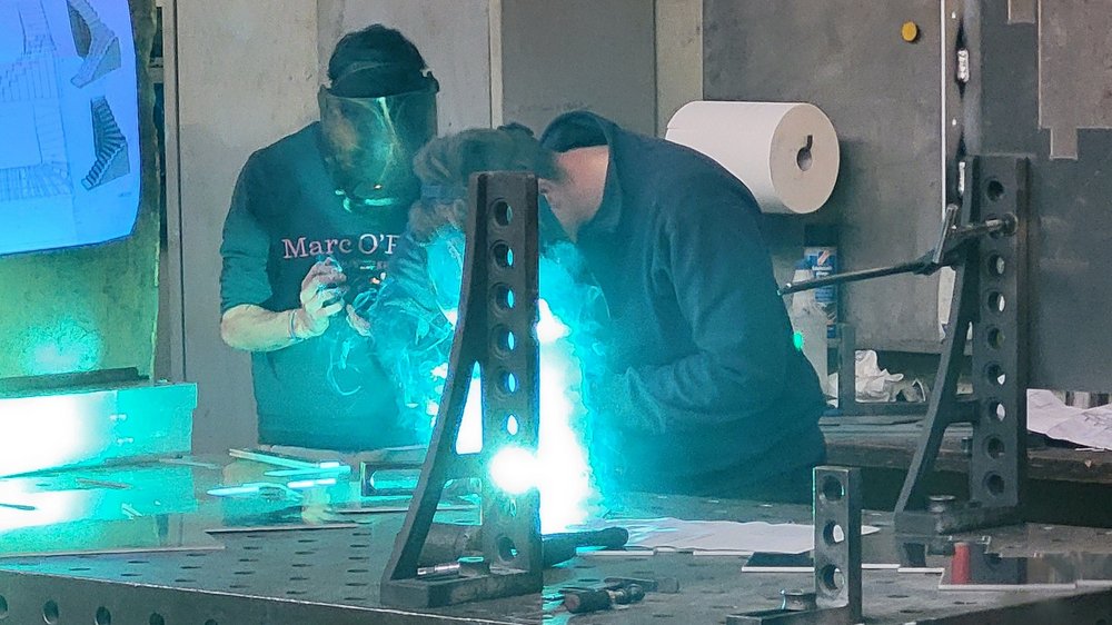 Home Zwei Personen schweißen mit Schutzmaske an Metallteile in Werkstatt