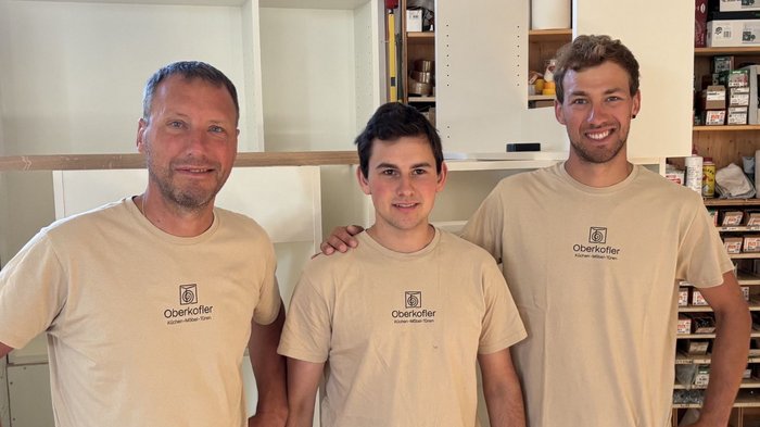 Mittelschule Klausen: Traumberufe in Gastgewerbe, Handwerk, Handel und Dienstleistungen vorgestellt Drei Männer in beigefarbenen Oberkofler-T-Shirts stehen vor einem Regal