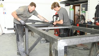 News Due uomini lavorano a una struttura in metallo in una officina