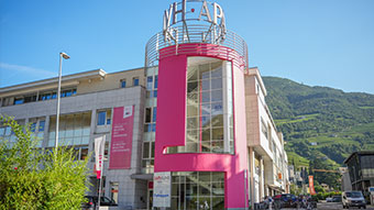 Home Modernes Gebäude mit rotem Glasaufzug und Bergen im Hintergrund
