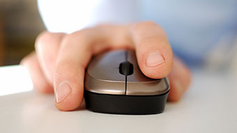 Home Hand die eine graue Computermaus auf weißem Tisch bedient